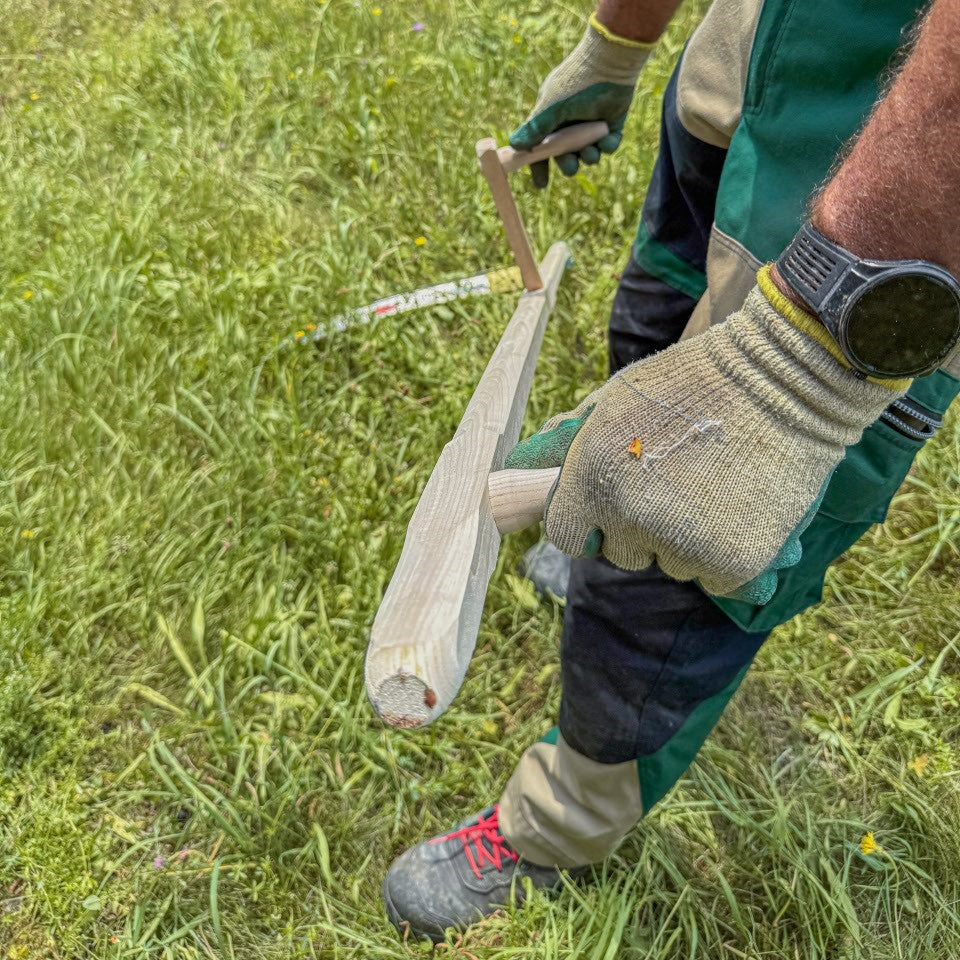 Detailaufnahme der Handhaltung an den zwei Holzgriffen der SHW Sense Friedrichstal mit Holzworb. Gärtner führt die traditionelle Handsense mit beiden Händen beim Mähen einer Wiese.