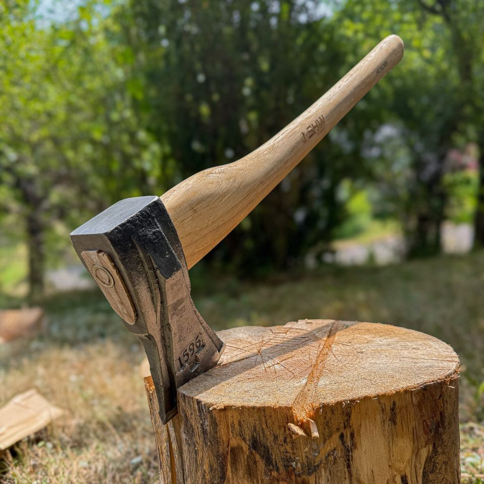 SHW Spaltaxt mit geschmiedetem Stahlkopf und ergonomisch geformtem Hickorystiel steckt in einem Holzklotz im Garten. Holzspaltaxt zum Spalten von Brennholz und Kaminholz.